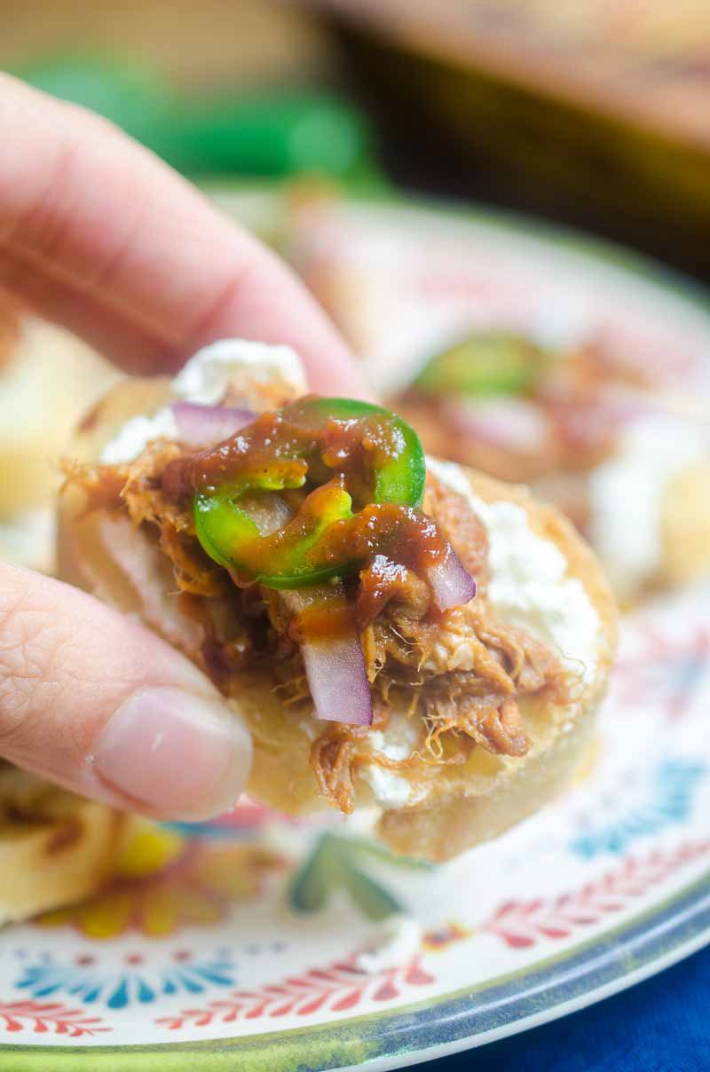  BBQ Pulled Pork Bruschetta is topped with goat cheese, Curly’s RoadTrip Eats West Coast IPA Style Pulled Pork, onions, jalapenos and BBQ sauce. It’s perfect for game day!