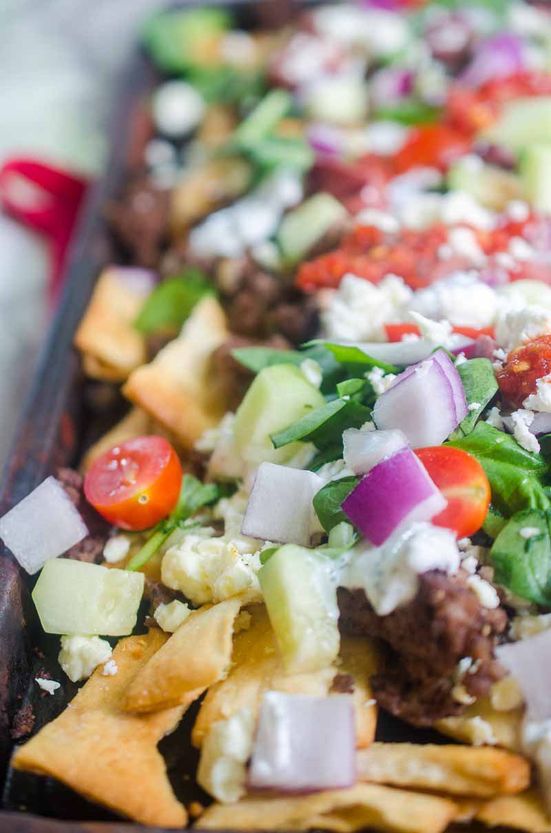 Fully loaded Greek Gyro Nachos with pita chips, tzatziki sauce, tomatoes, onions, cucumbers, olives and a whole lotta feta.