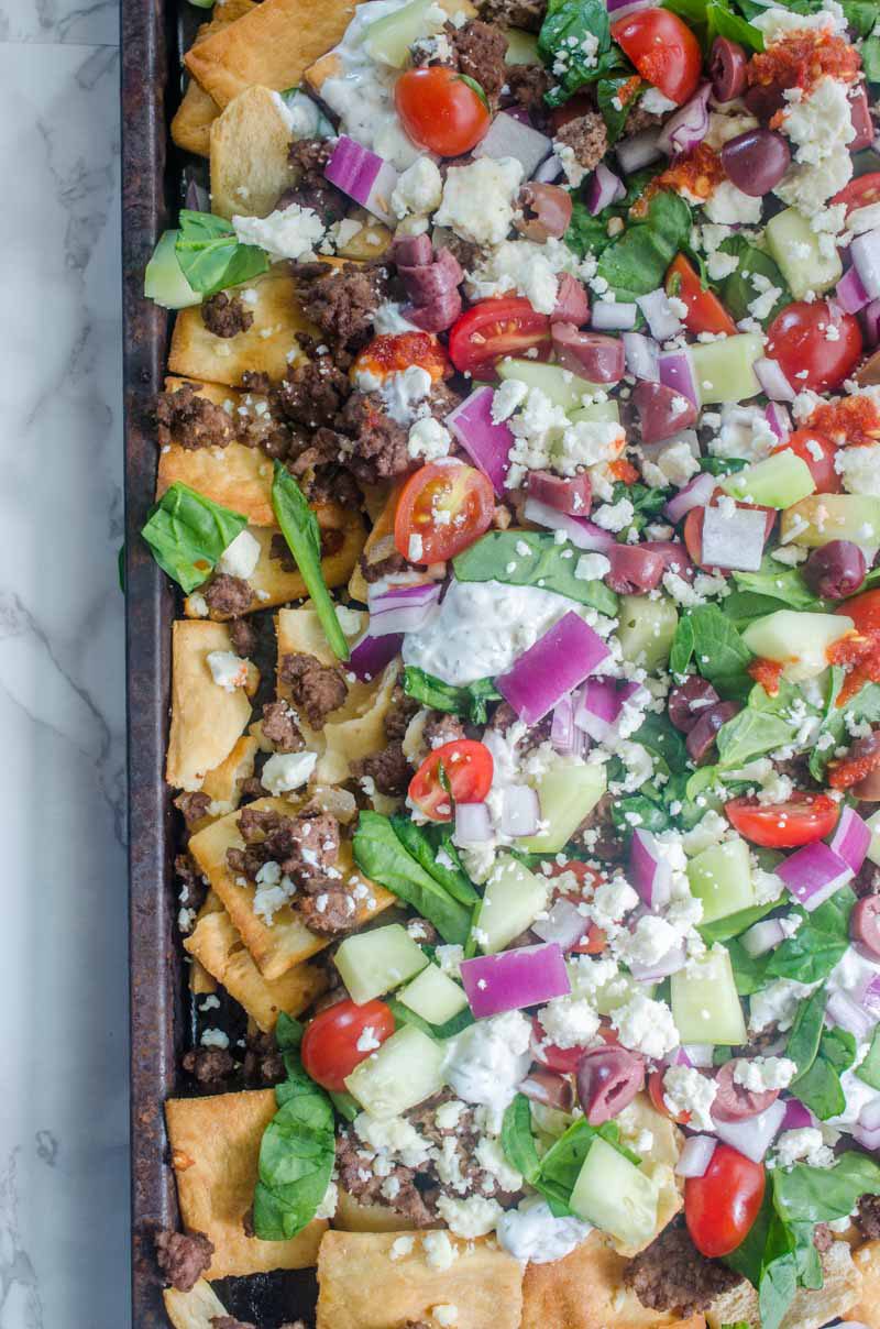 Fully loaded Greek Gyro Nachos with pita chips, tzatziki sauce, tomatoes, onions, cucumbers, olives and a whole lotta feta. 