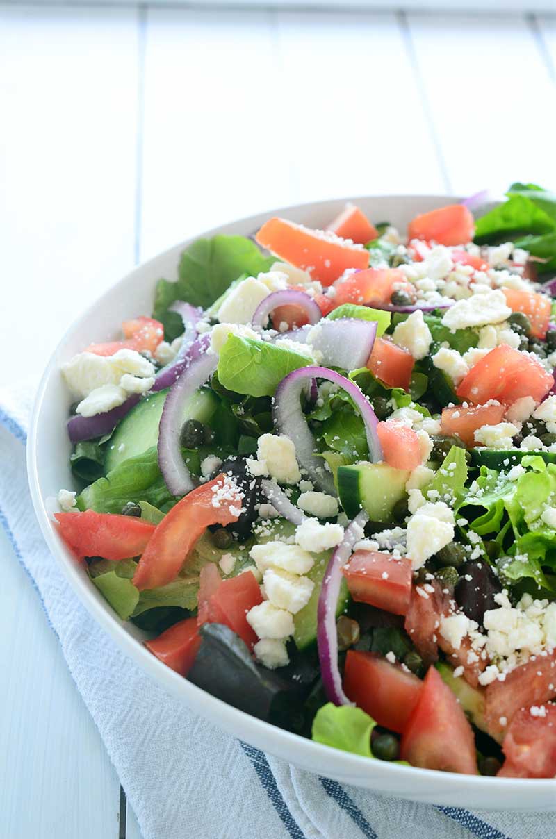 This Loaded Greek Salad has all kinds of goodies: olives, tomatoes, cucumbers, red onion, capers and feta and is tossed in a tangy Oregano vinaigrette.