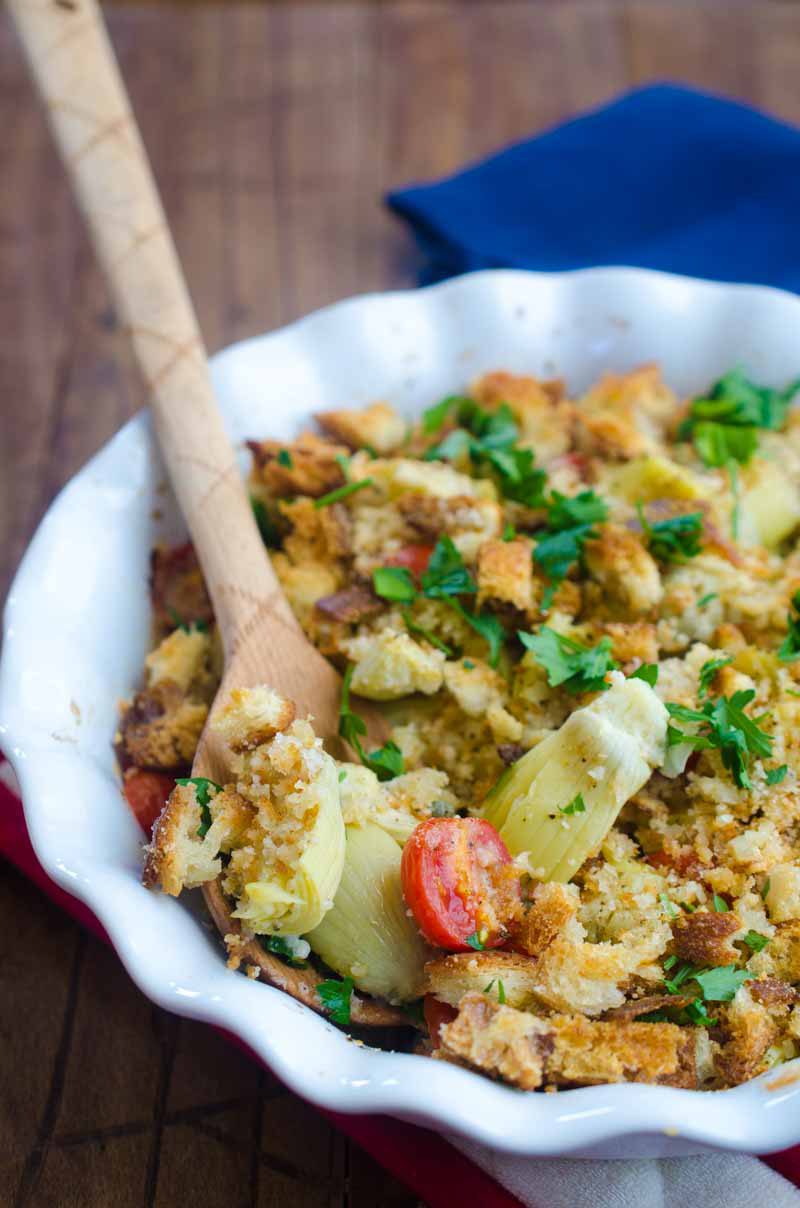 Tomato Artichoke Bake is the perfect side! It's loaded with artichoke hearts, fresh bread crumbs, tomatoes, grated parmesan and then baked until golden.
