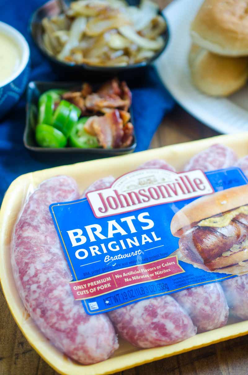 Ultimate cheesy brats are loaded with caramelized onions, cheese sauce, jalapeños and bacon. They are the perfect way to celebrate National Bratwurst day! #ad