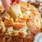 A hand pulling a cube of pull apart bread.