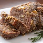 sliced rosemary garlic meatloaf on white plate.