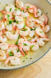 Side angle photo of garlic butter shrimp in a pan.