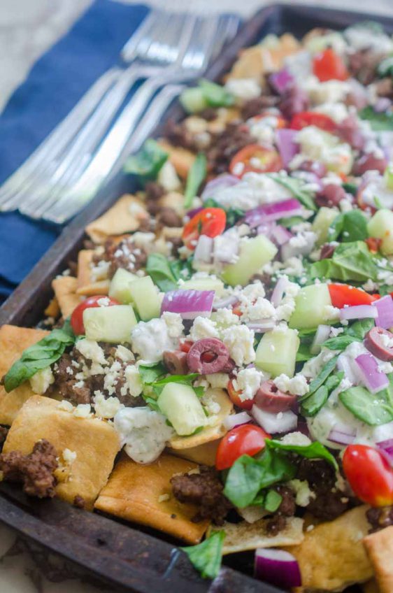 Fully loaded Greek Gyro Nachos with pita chips, tzatziki sauce, tomatoes, onions, cucumbers, olives and a whole lotta feta.