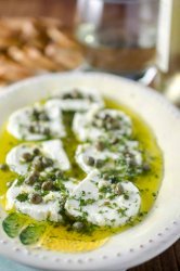 Tangy herb marinated goat cheese is the perfect appetizer to enjoy with a glass of wine.