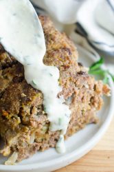 Spooning meatloaf sauce over a slice of meatloaf.