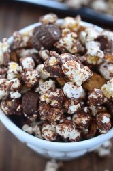 Peanut Butter Cup S'mores Popcorn - one heck of a salty/sweet snack. It is loaded with popcorn, peanut butter cups, marshmallows, graham cereal and chocolate.