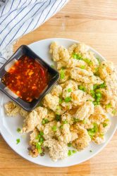 Fried Salt and Pepper Calamari on a white plate with sweet thai chili sauce.