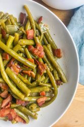Southern Style Green Beans with Bacon is a comfort food classic. Fresh green beans slow simmered with onions, chicken broth and bacon. Perfect for holidays and Sunday supper! 