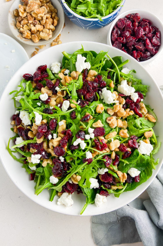 Overhead photo of spinach cranberry salad in a white bowl.