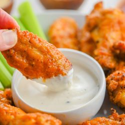 Hand holding chicken wings.