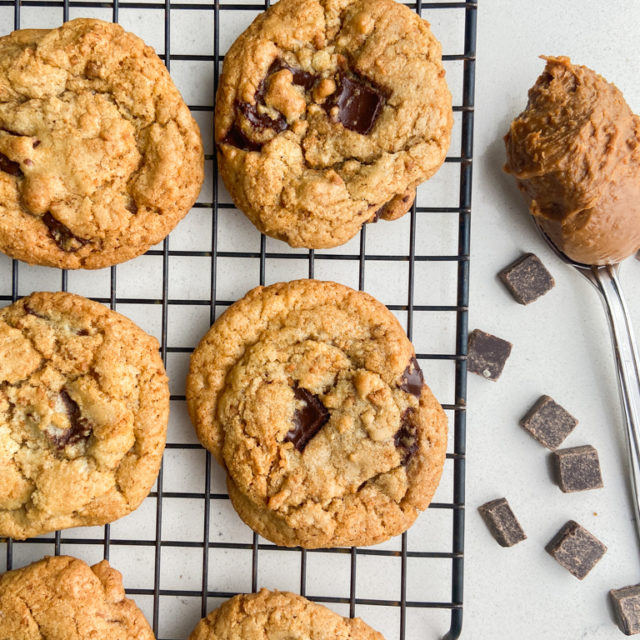 Overhead photo of biscoff and dark chocolate chip cookies on a cooling rack with a scoop of biscoff spread.