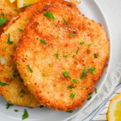 Fried Calamari Steak on white plate with parsley on top.