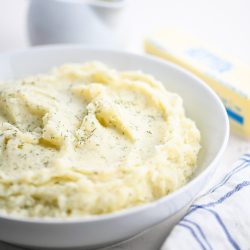 dill mashed potatoes in white bowl.