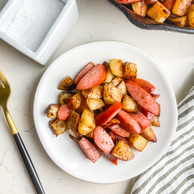 Overhead photo of potatoes and sausage on a white plate.