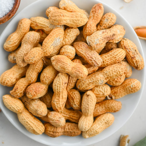 Oven roasted peanuts on white plate.