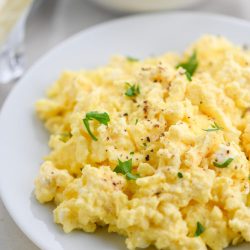 Truffle scrambled eggs on a white plate.