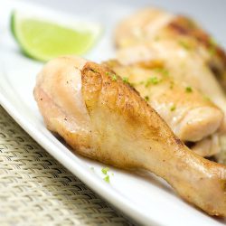adobo lime chicken on white plate with sliced lime.