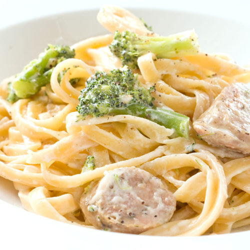 creamy broccoli fettuccine on white plate.