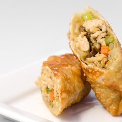 chicken egg roll cut in half on a white plate.