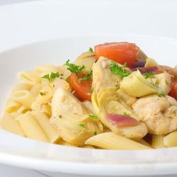 chicken with artichokes and tomatoes in a white bowl.