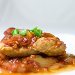 Chili pepper chicken on white plate.