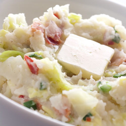Colcannon in white bowl with pad of butter on top.