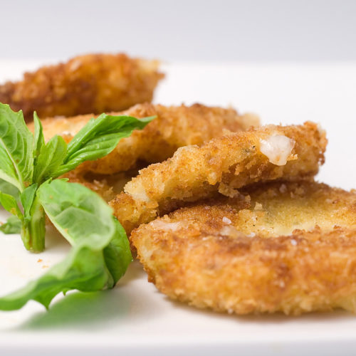 Crispy marinated mozzarella on white plate.