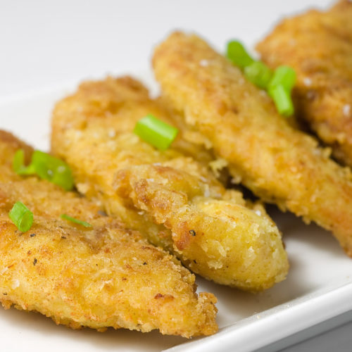 Curried chicken tenders on white plate.