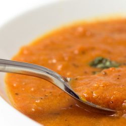 Close up of spoon in a bowl of fire roasted tomato soup.
