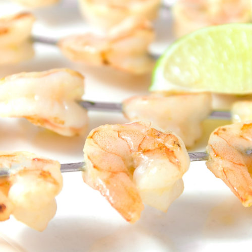 garlic and lime shrimp skewers on white plate.