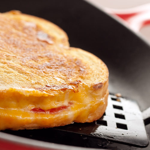 Grilled cheese tomato sandwich in a skillet.