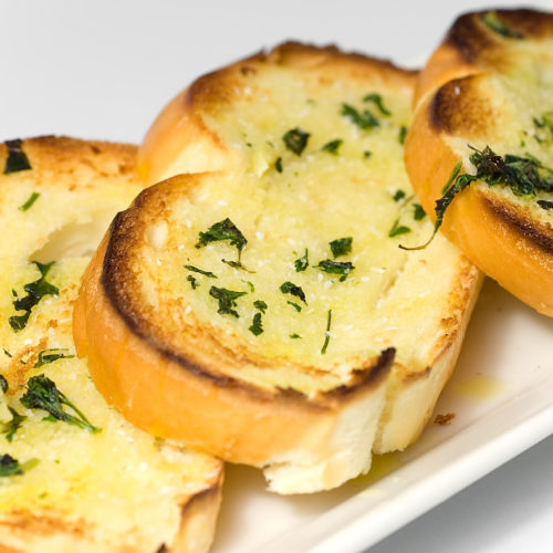close up of herb garlic bread on white plate.