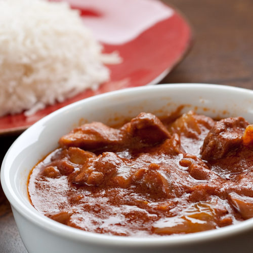 Indian butter chicken in white dish with rice.