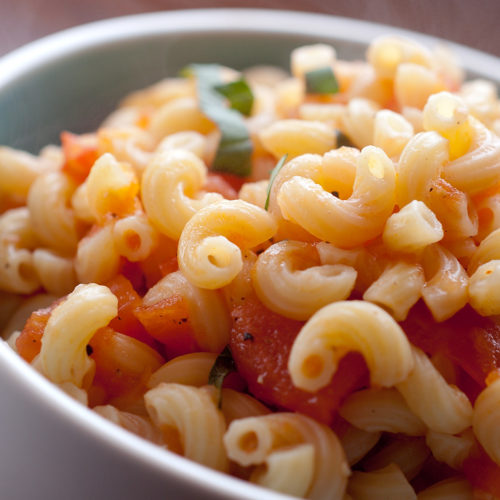macaroni and tomatoes in white bowl.