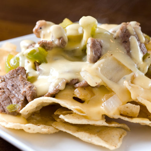 Philly cheesesteak nachos on plate.