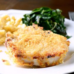 Potato chip crusted pork chops on white plate.