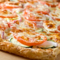 Puff pastry vegetable pizza on cutting board.