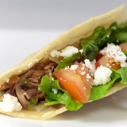 taco filled with pulled pork, lettuce, tomato and cheese.