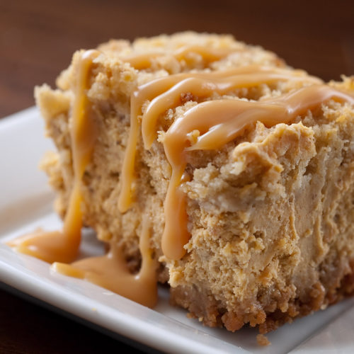 one pumpkin cheesecake bar on plate drizzled with caramel.