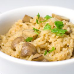 Rice pilaf with crimini mushrooms in white bowl.