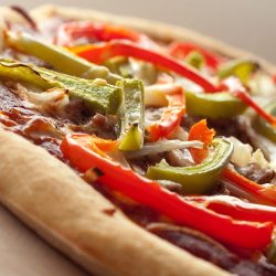 Sausage pepper and onions pizza on cutting board.