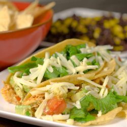 two chicken tacos on white plate.