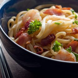 Shrimp and bacon linguine in blue bowl.