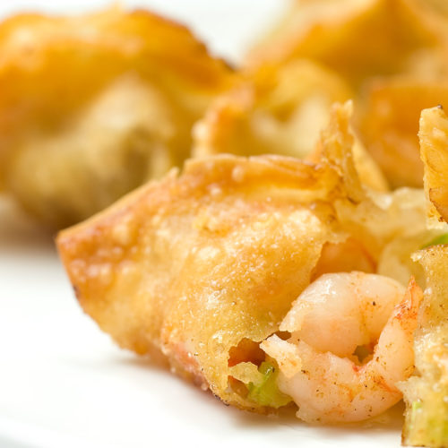 close up of opened shrimp and vegetable wonton on white plate.