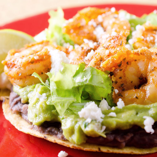 Shrimp tostadas on red plate.