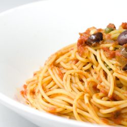 Spaghetti puttanesca in white bowl.