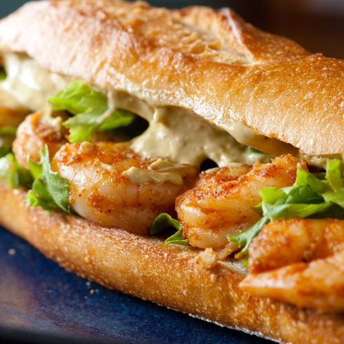 Spicy shrimp sandwich on blue plate.